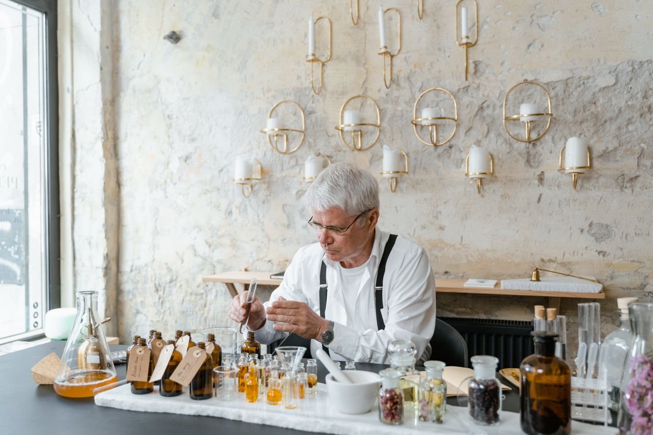 Mastering the First Impression: Your intriguing post title goes here Senior perfumer blends fragrant ingredients in stylish indoor setting.
