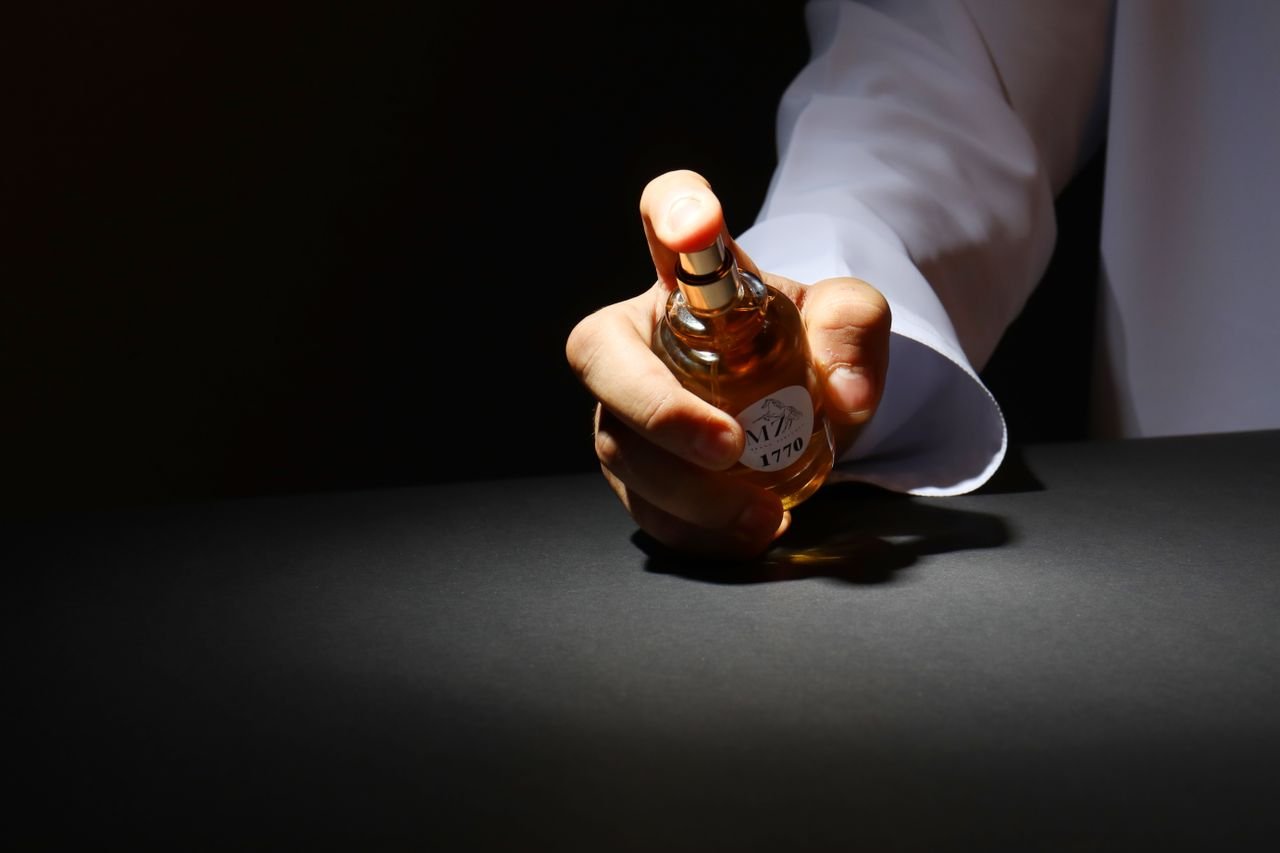 Crafting Captivating Headlines: Your awesome post title goes here A dramatic close-up of a hand holding a perfume bottle against a dark background, highlighting elegant design.
